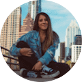 A woman sitting on the ground in front of some buildings