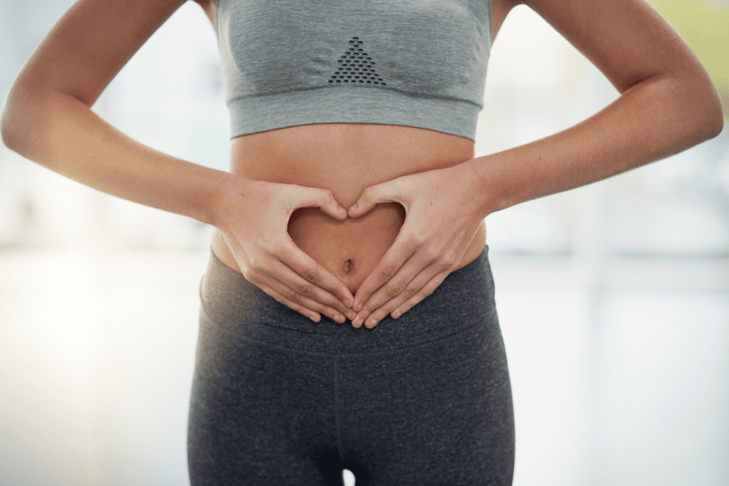 A woman holding her stomach in the shape of a heart.