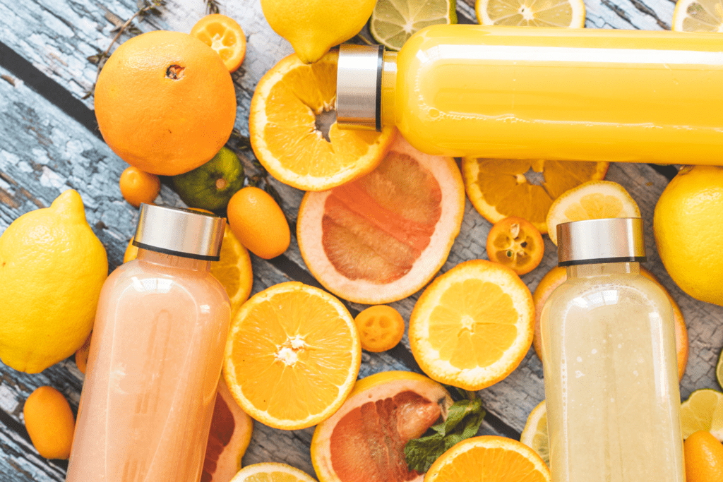 A table topped with citrus fruits and bottles of juice.